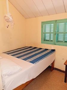 a bedroom with a bed and a green window at Auberge Mariama BA in Gorée