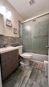 La salle de bains est pourvue de toilettes et d'une douche en verre. dans l'établissement Oasis Wynwood, à Miami