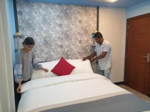 two people standing next to a bed in a room at Isle inn {Fuvahmulah) in Fuvahmulah