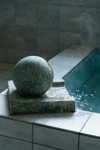 a large rock sitting next to a pool of water at koti hakone（コティ箱根） in Hakone