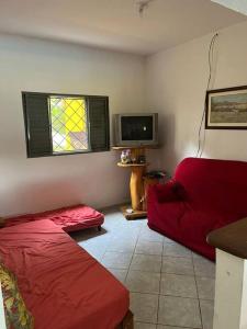 een woonkamer met een rood bed en een televisie bij Meu Pequeno Paraíso in Pinhalzinho