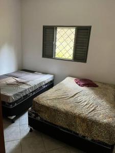 2 aparte bedden in een kamer met een raam bij Meu Pequeno Paraíso in Pinhalzinho