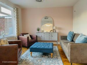 a living room with a couch and a blue stool at Large villa sleeping 8 under 5 minute walk to beach in Caister-on-Sea +46 photos