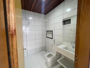 a white bathroom with a toilet and a sink at Cama & Café Parecis in Campo Novo do Parecis