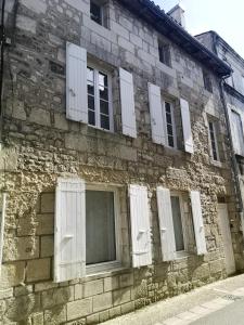 un antiguo edificio de piedra con ventanas blancas contraventanas en La Demeure des Artistes - Quartier historique en Saintes