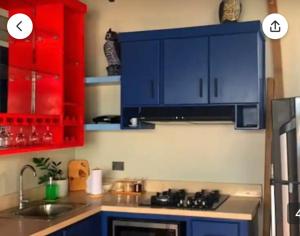 uma cozinha com armários vermelhos e azuis e um lavatório em Rooftop Paradise em San Francisco de Macorís