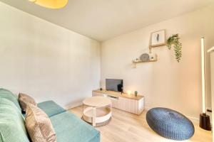 a living room with a couch and a tv at Le Verde - Bel appartement cosy in Saint-Genis-Laval