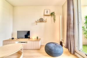 a living room with a television and a table at Le Verde - Bel appartement cosy in Saint-Genis-Laval