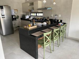 a kitchen with a black counter and green chairs at Casa de Campo em Bananeiras-PB in Bananeiras