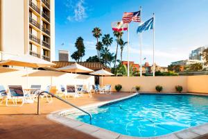 een zwembad in een hotel met vlaggen, tafels en stoelen bij Four Points by Sheraton San Diego Downtown Little Italy in San Diego