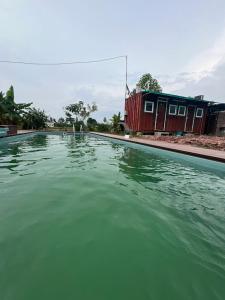 una piscina de agua verde frente a un edificio en HOMESTAY Kampong KOTA AUR Resort with swimming pool, Kepala Batas, SEBERANG PERAI, PENANG -MOTAC registered Awarded ASEAN homestay standard Malaysia AWARD 2023-2025 Only 3 minutes from viral KG AGONG, en Kepala Batas