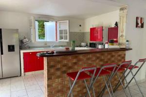 uma cozinha com armários vermelhos e cadeiras vermelhas em VILLA PISCINE PLEIN SUD MARTINIQUE ALIZESDESCAPS em Sainte-Anne