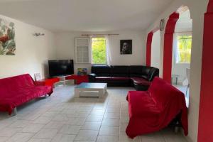 uma sala de estar com um sofá preto e cadeiras vermelhas em VILLA PISCINE PLEIN SUD MARTINIQUE ALIZESDESCAPS em Sainte-Anne