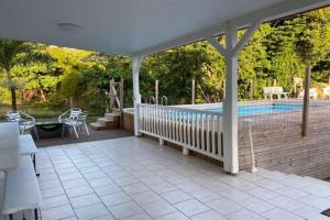 eine Terrasse mit Pool und ein Haus in der Unterkunft VILLA PISCINE PLEIN SUD MARTINIQUE ALIZESDESCAPS in Sainte-Anne