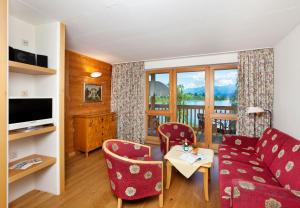 ein Wohnzimmer mit einem Sofa und Stühlen sowie einem Balkon in der Unterkunft Appartement-Hotel Seespitz in Füssen