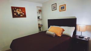 a bedroom with a bed with an orange pillow at Estudio Luxury zona 13 Aeropuerto in Guatemala