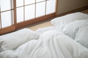 an unmade bed with white sheets in a room with windows at Yuzawa House - Vacation STAY 07080v in Yuzawa