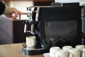 una persona che versa il caffè in una macchina da caffè di Yuzawa House - Vacation STAY 07080v a Yuzawa