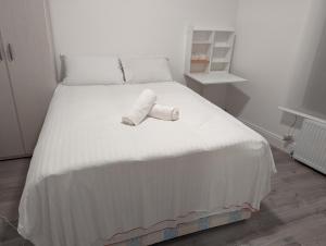 ロンドンにあるMile End Roomsの白いベッド(ロールアップタオル付)