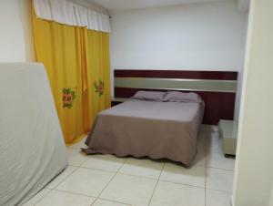 1 dormitorio con cama, cortinas y suelo de baldosa en Casa da Vó Bia, en Caparaó Velho