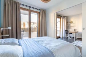 a bedroom with a bed and a balcony with a desk at Charming apartment near Paris in Vincennes