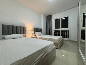 a bedroom with two beds and a window at Luxury Inn: 2BR Prime location in Madinaty B12 in Madinaty