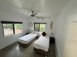 2 Betten in einem Zimmer mit weißen Wänden und Fenstern in der Unterkunft Elluk East Studios in Port Vila