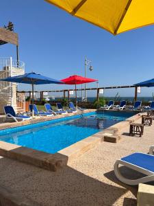 a large swimming pool with chairs and umbrellas at Lilly Lounge and Pool Accommodation for Adults Only in Hurghada