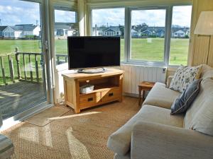 sala de estar con TV de pantalla plana sobre una mesa en Bacton Seaview Bungalow, en Bacton