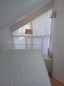 Un dormitorio con una cama blanca y una ventana. en ZIL - Studio Apartment City Center, en Zagreb