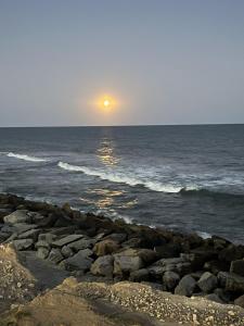 - un coucher de soleil sur l'océan avec des rochers dans l'établissement Hangar 15, à Playa Dorada