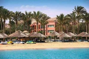 a resort with straw umbrellas and boats on a beach at قرية بالميرا السخنه in Ain Sokhna