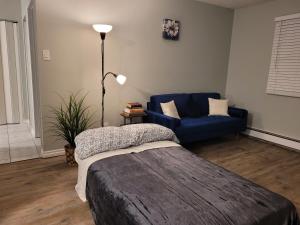 un soggiorno con letto e divano blu di Entire 1-Bedroom Unit in Vibrant 124 Street Arts District a Edmonton