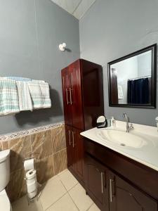 a bathroom with a sink and a toilet and a mirror at Cuco Beach Paradise Villa in Chirilagua
