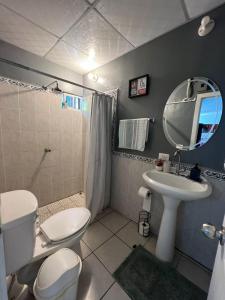 a bathroom with a toilet a sink and a mirror at Cuco Beach Paradise Villa in Chirilagua