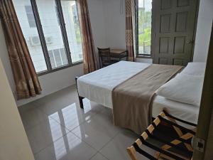 a bedroom with a bed and two windows and a door at FIJI HOME Apartment Hotel in Suva