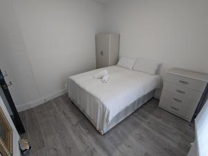 ロンドンにあるMile End Roomsの小さなベッドルーム(白いベッド1台、ドレッサー付)