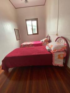 a bedroom with two beds with red sheets and a window at Quarto casa Guaporé in Guaporé