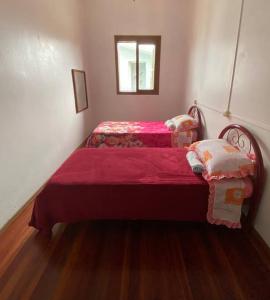 a bedroom with two beds with red sheets and a window at Quarto casa Guaporé in Guaporé
