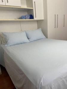 a white bed with blue pillows in a bedroom at Quarto casa Guaporé in Guaporé