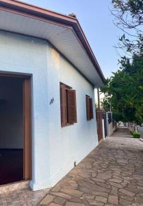 a white building with a door next to a sidewalk at Quarto casa Guaporé in Guaporé