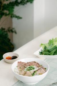 ein weißer Tisch mit drei Schüsseln Essen drauf in der Unterkunft Lộc Nguyên Hotel Dalat in Xuan An