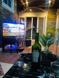 a bottle of wine and two glasses on a table at City Villa in Tagbilaran City