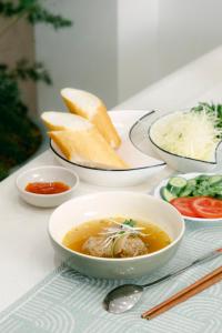 einen Tisch mit Schalen Suppe und Gemüse in der Unterkunft Lộc Nguyên Hotel Dalat in Xuan An