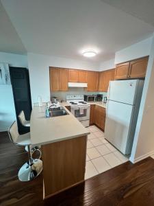 a kitchen with wooden cabinets and a white refrigerator at Downtown Toronto Suite By The Lake in Toronto