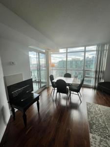 een woonkamer met een tafel en stoelen en een piano bij Downtown Toronto Suite By The Lake in Toronto