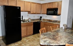 a kitchen with a black refrigerator and wooden cabinets at Grand Smokies Resort Lodge Pigeon Forge in Pigeon Forge