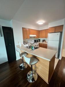 a kitchen with wooden cabinets and a island with bar stools at Downtown Toronto Suite By The Lake in Toronto