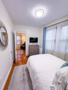 a bedroom with a white bed and a television at Longwood Medical Condominium in Brookline