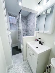 a white bathroom with a sink and a mirror at Longwood Medical Condominium in Brookline